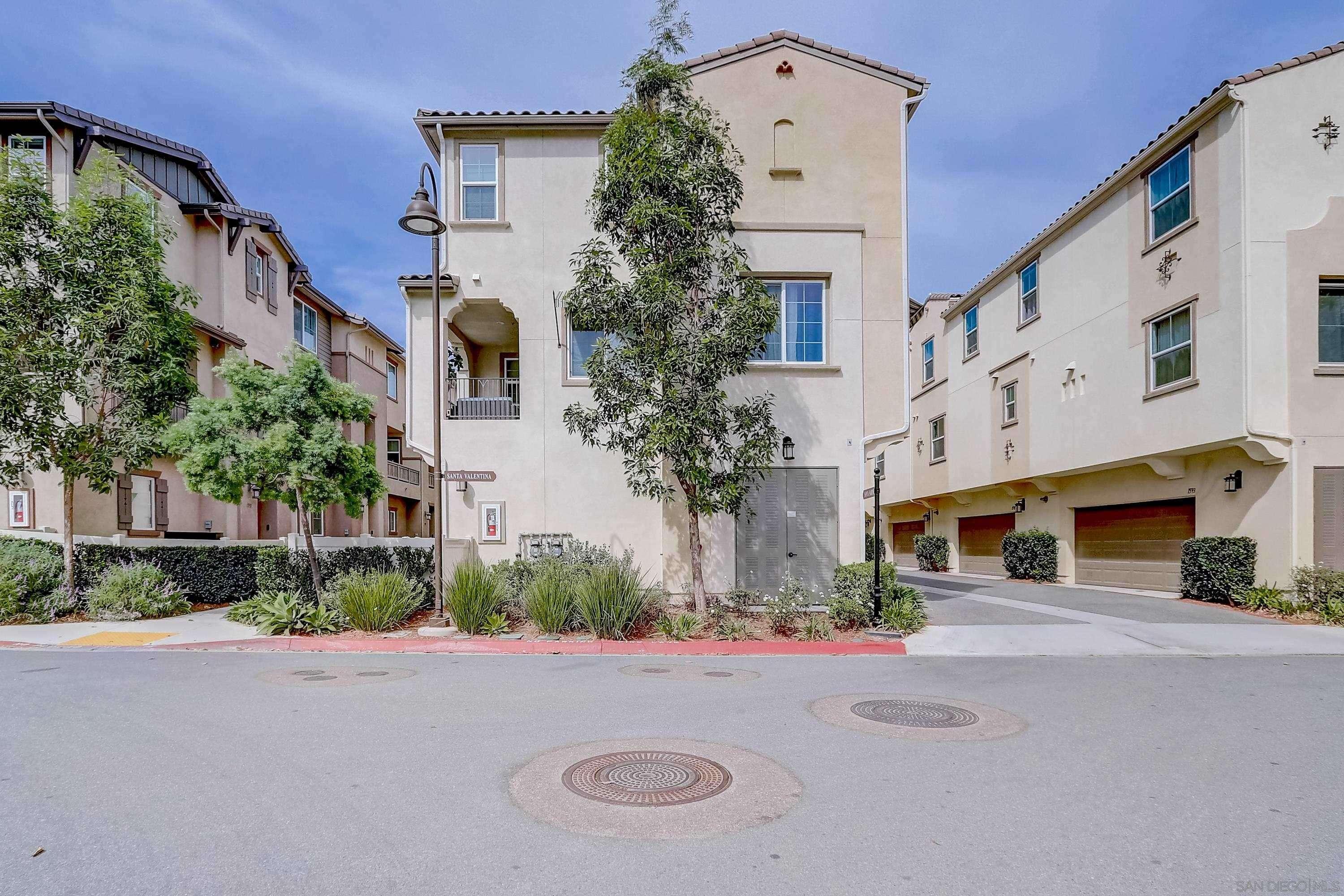 A light colored stucco condo building surrounded by small trees and drought-friendly landscaping